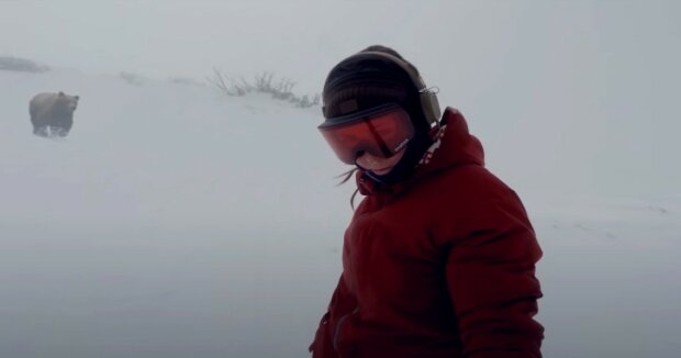 Eine Frau fuhr Snowboard, als ihr ein großer Bär nachlief